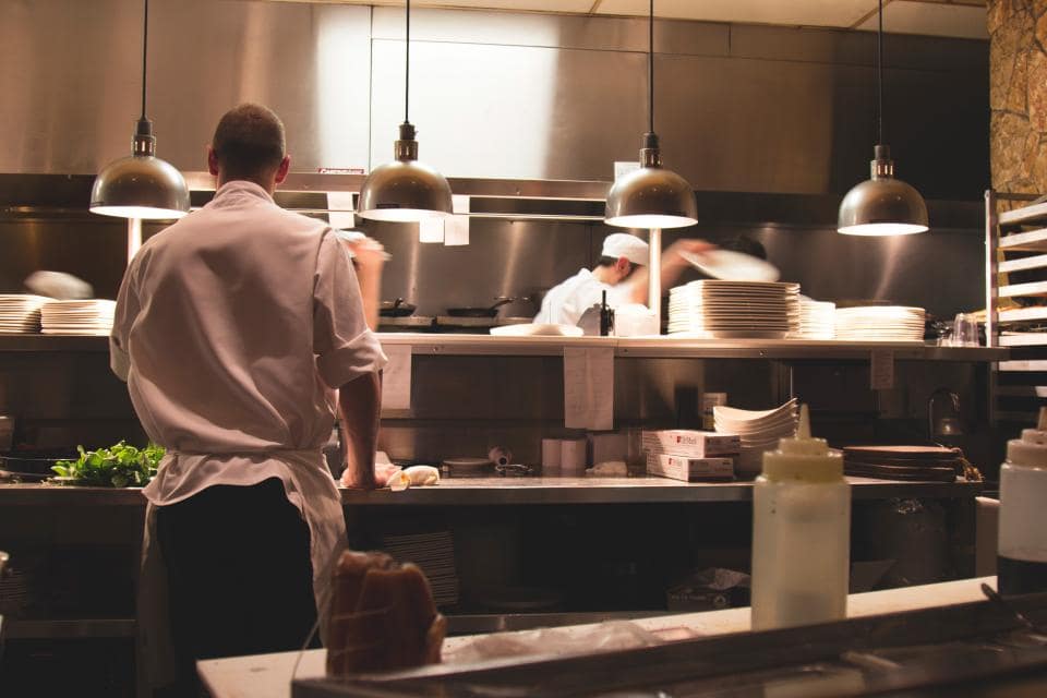A working restaurant kitchen line during service, seen from behind the pass.