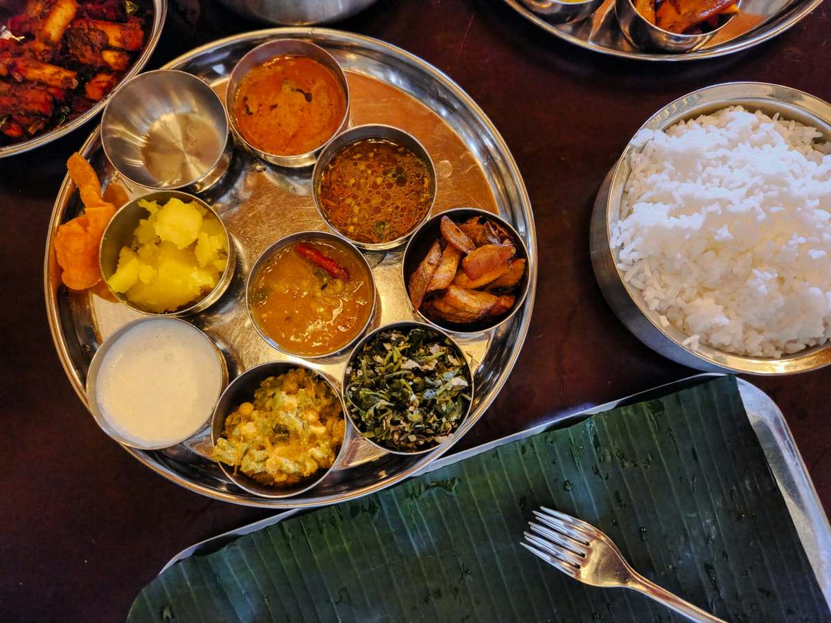 A thali of rice, dal and vegetables laid out on a banana leaf.